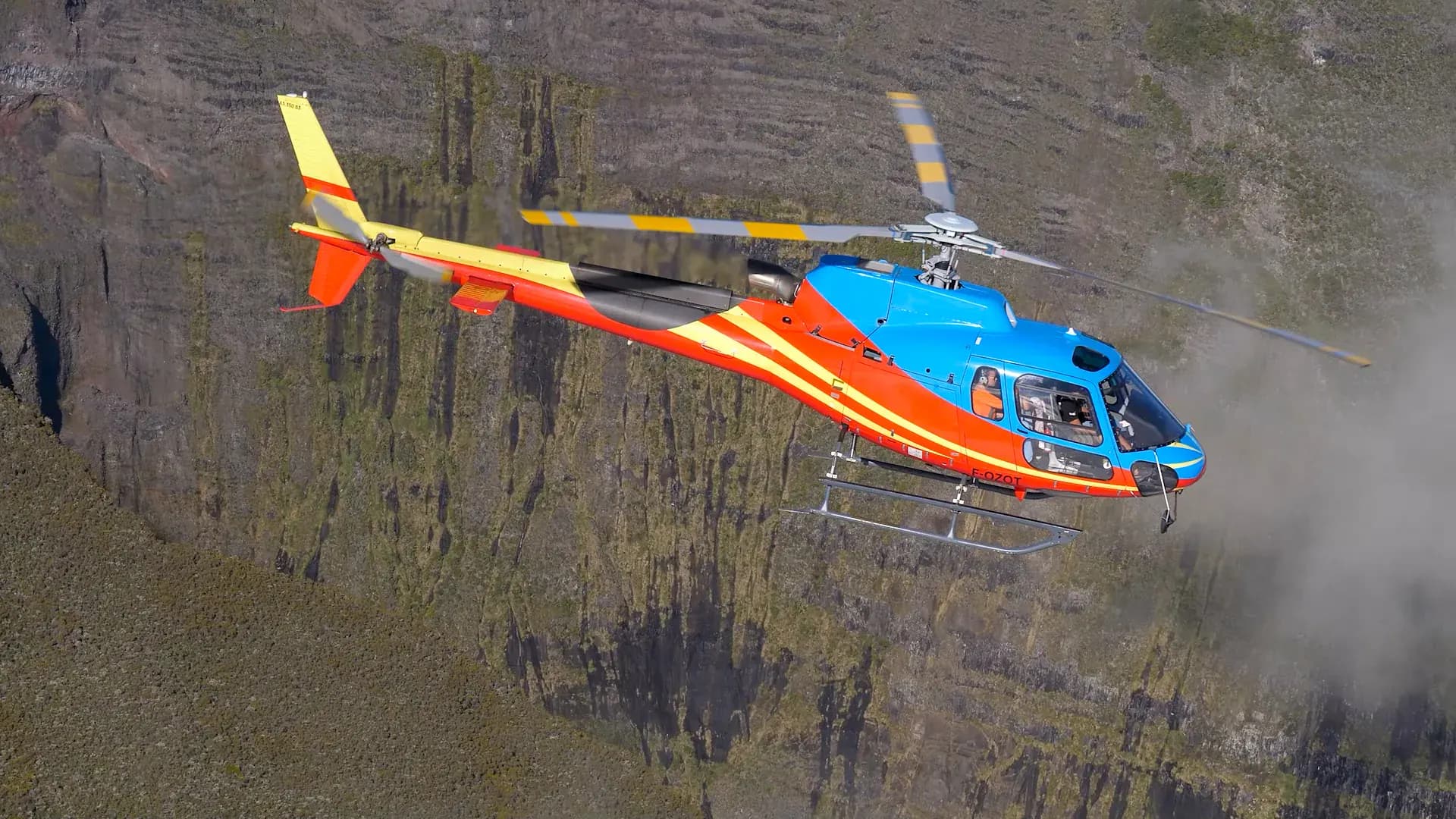 Hélicoptère F-OZOT Helireunion en vol devant un rempart de La Réunion